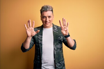 Young handsome modern man wearing business jacket standing over yellow isolated background showing and pointing up with fingers number nine while smiling confident and happy.