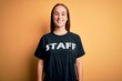 Young beautiful worker woman wearing staff uniform t-shirt over isolated yellow background with a happy and cool smile on face. Lucky person.