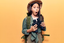 Beautiful Child Girl Wearing Explorer Hat Holding Binoculars Scared And Amazed With Open Mouth For Surprise, Disbelief Face