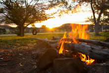 Close Up Image Of Camp Fire Burning With Tire Swing And Sunset In The Background