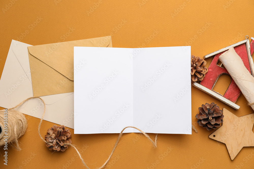 Christmas composition with blank card and envelopes on color background