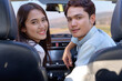 © PK Studio - Young couple in his car, happy to drive on a country road. Happy young women and young men in car