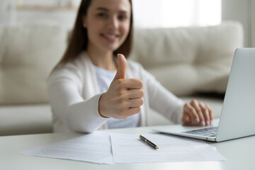 Woman sit at coffee table at home near laptop smile show at camera thumbs up gesture, close up. Good terms new mobile e-bank, e-services, buy insurance, satisfied client give positive feedback concept