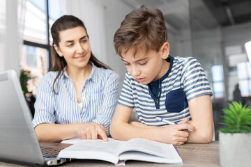 Wall Mural - education, family and homework concept - smiling mother and son with book writing to notebook at home