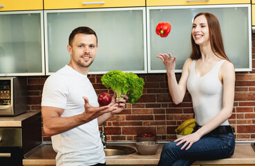 Young attractive man and woman in the kitchen holding vegetables and fruits. Healthy food concept. Diet for family, healthy lifestyle