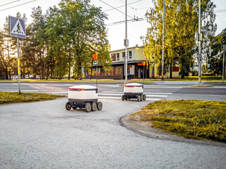 Some Delivery robots on the street. Estonian Cyber-couriers in Tallinn city. Sunny summer day. Copy space. Fitered image. the concept of new technology.