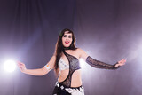 Fototapeta Panele - Young woman belly dancer in exotic dress with gold, dancing tribal fusion dance in studio.