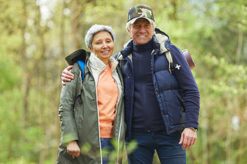 Wall Mural - waist up portrait of cheerful senior couple looking at camera while enjoying hike in beautiful fores