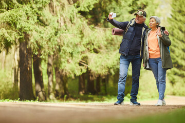 Wall Mural - full length portrait of active senior couple taking selfie photo via smartphone while enjoying hike 