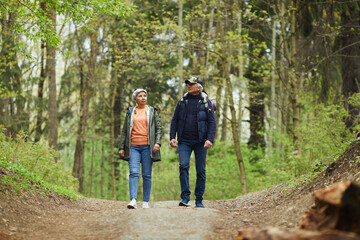 Wall Mural - full length portrait of active senior couple walking towards camera while enjoying hike in beautiful