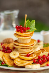 Canvas Print - Mini pancakes canape with banana, honey, red currant. Garden. Natural light. 