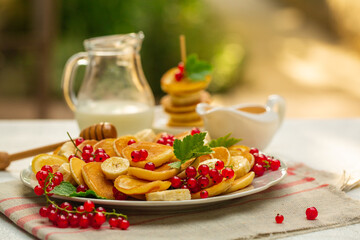 Poster - Morning. Breakfast with mini pancakes, honey, red currant, banana. Milk jar. Garden. Natural light. 