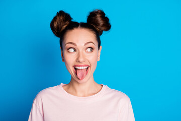 Wall Mural - Closeup photo of attractive childish lady two funny buns stick tongue out mouth teasing boyfriend avoid look eyes bad behavior wear casual pink t-shirt isolated bright blue color background