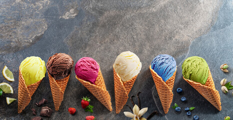 Fototapete - Set of various colorful ice creams in waffle cones with fruits slices on the grey background.