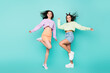 Full body photo of two pretty crazy ladies friends youth clothes rejoicing dancing party moves hairdo flight wear cropped pullovers mini skirts shoes isolated pastel teal color background