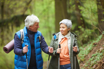 Wall Mural - waist up portrait of active senior couple looking at each other and smiling while enjoying nordic wa