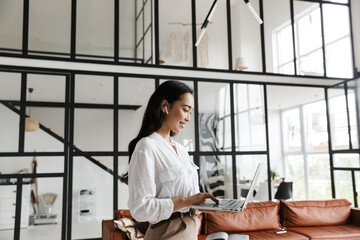 Wall Mural - Attractive young brunette asian woman using laptop