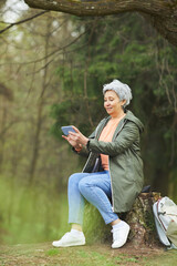 Wall Mural - vertical full length portrait of active senior woman using smartphone for video chat while enjoying 