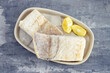 frozen raw cod fish with ice on dish on ceramic background