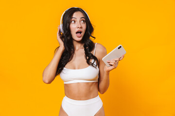 Sticker - Image of surprised woman in swimsuit using cellphone and headphones