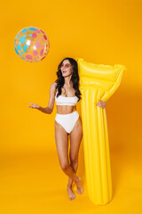 Wall Mural - Image of delighted woman in swimsuit posing with ball and air mattress