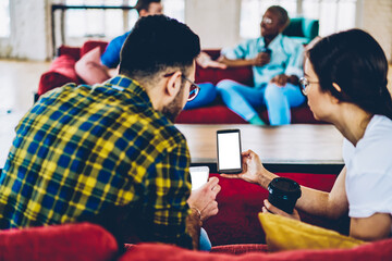 Poster - cropped back view of casual dressed young people watching live stream in blog on modern smartphone w