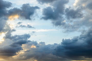 Wall Mural - bright blue sky is visible through the gap in the dark clouds at evening. rain clouds surround the l