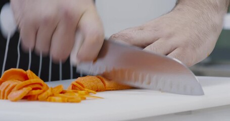 Wall Mural - Professional chef slicing fresh carrots on cutting board