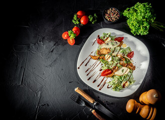 Wall Mural - Chicken caesar salad with grilled chicken on plate. Grilled chicken breasts and fresh salad in plate on a dark background. Top view wiht copy space