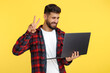 © Screaghin - Stylish bearded hipster young man in plaid shirt holding notebook and show peace gesture over yellow background.