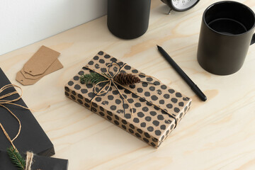 Sticker - Kraft and black christmas gifts with workspace accessories on a wooden table.