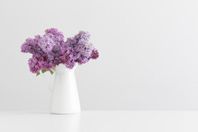 Bouquet Of Lilac Flowers In A Vase On A White Table With Blank Copy Space.