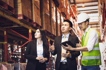 Wall Mural - Asian male foreman or manager showing report from digital tablet to business man and woman or CEO in warehouse company. people discuss of logistics shipping, quality control or export import goods.