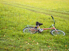 Red Bicycle Lie On Summer-autumn Feild On Grass. Rest In The Countryside