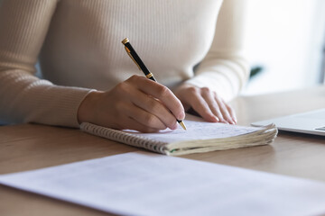 Close up student girl sit at desk holding pen makes notes on exercise book, do task prepare for college exams, female entrepreneur write down important data information creative start up ideas concept