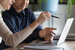 © fizkes - Close up view indian caucasian women colleagues discuss project working on common task using laptop sit at desk in workplace pointing at screen learn new app do data research analysis together concept