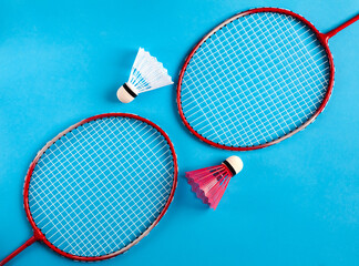 Sport flat lay with two rackets and two shuttlecocks for playing badminton on blue background. Concept healthy lifestyle. Top view.