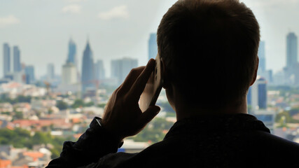 Man is talking on the phone in the background of the city.