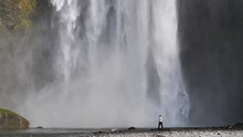 Man alone watching Skogafoss waterfall Iceland slow motion