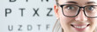 © H_Ko - Close-up of cheerful female ophthalmologist smiling on camera. Special board with letters to checkup vision. Copy space in left side. Modern medicine healthcare and eye doctor concept
