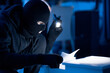 © Prostock-studio - Masked thief holding and reading confidential documents