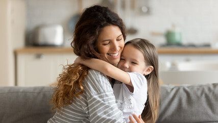 close up happy attractive mother hugging cute preschool daughter. smiling young mom closed eyes embr