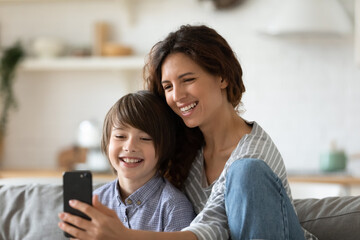 Close up happy young mother taking selfie with preschool son. Smiling attractive mom holding smartphone posing for photo with child. Family having fun together with modern mobile device.