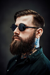 Wall Mural - Closeup portrait of a cool bearded male in sunglasses on a dark background
