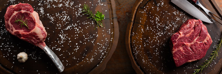 Wall Mural - Top view raw tomahawk and Chuck Eye  beef steak with ingredients for grilling with a spice rub, fresh rosemary and salt , on a table with dark wood texture and space for writing.