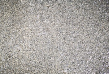 background of sand and small stones of gray color by the Ligurian sea