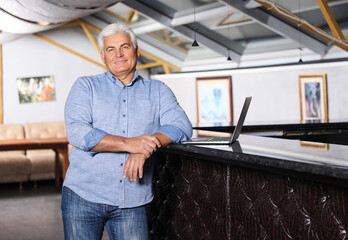 Senior business owner with laptop in his restaurant