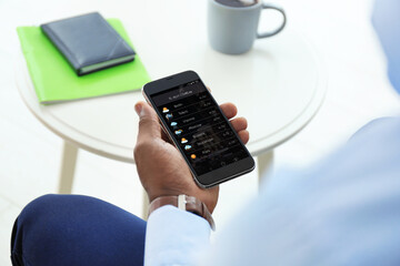 Wall Mural - african-american man using weather forecast app on smartphone indoors, closeup