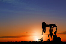 Silhouette Of Crude Oil Pump At Sunset. Space For Text