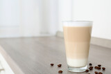 Delicious latte macchiato and coffee beans on wooden table indoors. Space for text